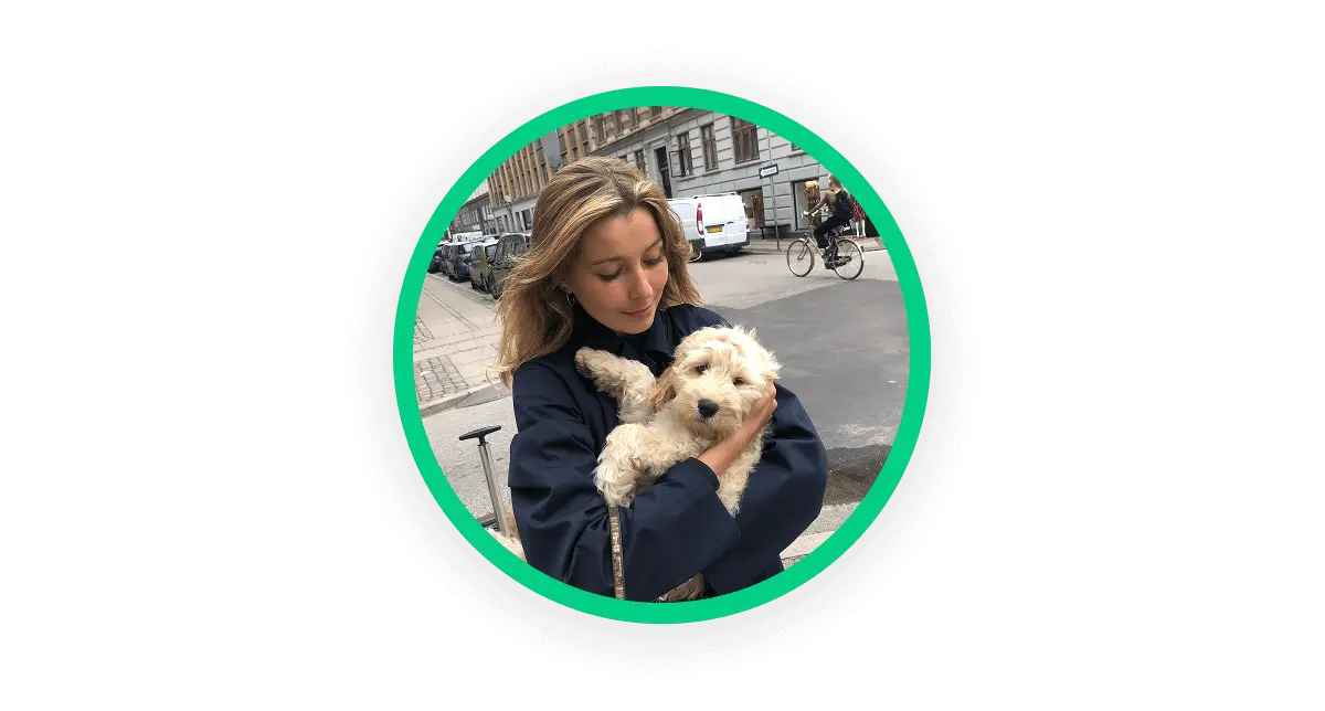 A circular image showing a photo of a woman holding her dog in her arms and looking down at it