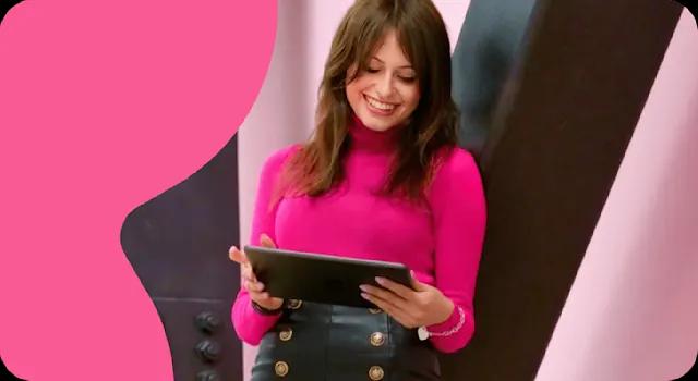 A photo of a Trustpilot employee looking down at her Tablet and smiling