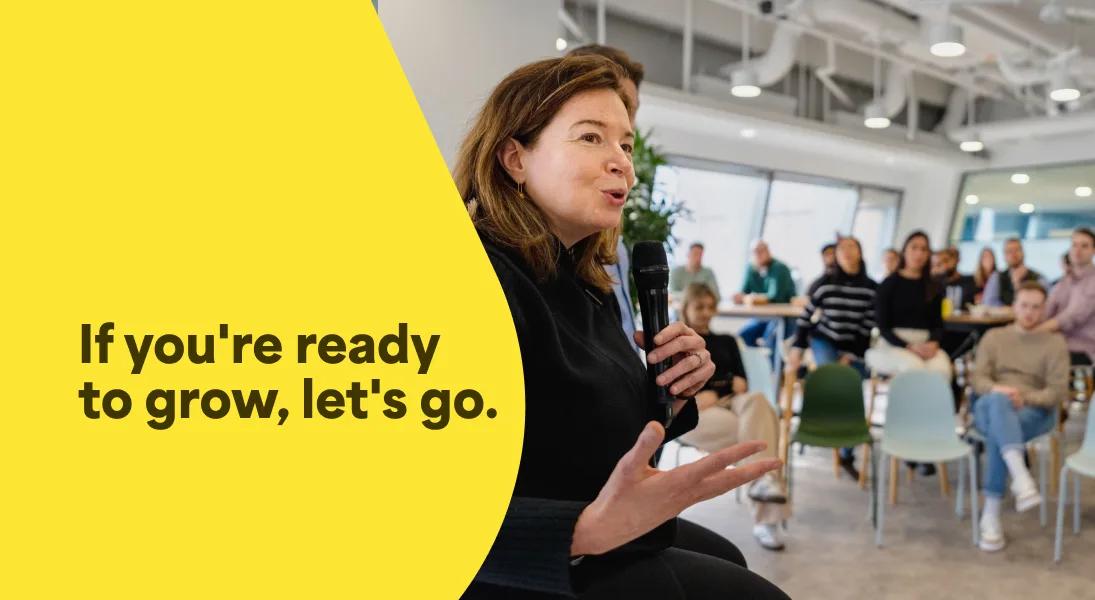 A photo of Alicia Skubick, Chief Customer Officer speaking at a company meeting in the Trustpilot office. The photo has an overlay of text that says If you're ready to grow, let's go.